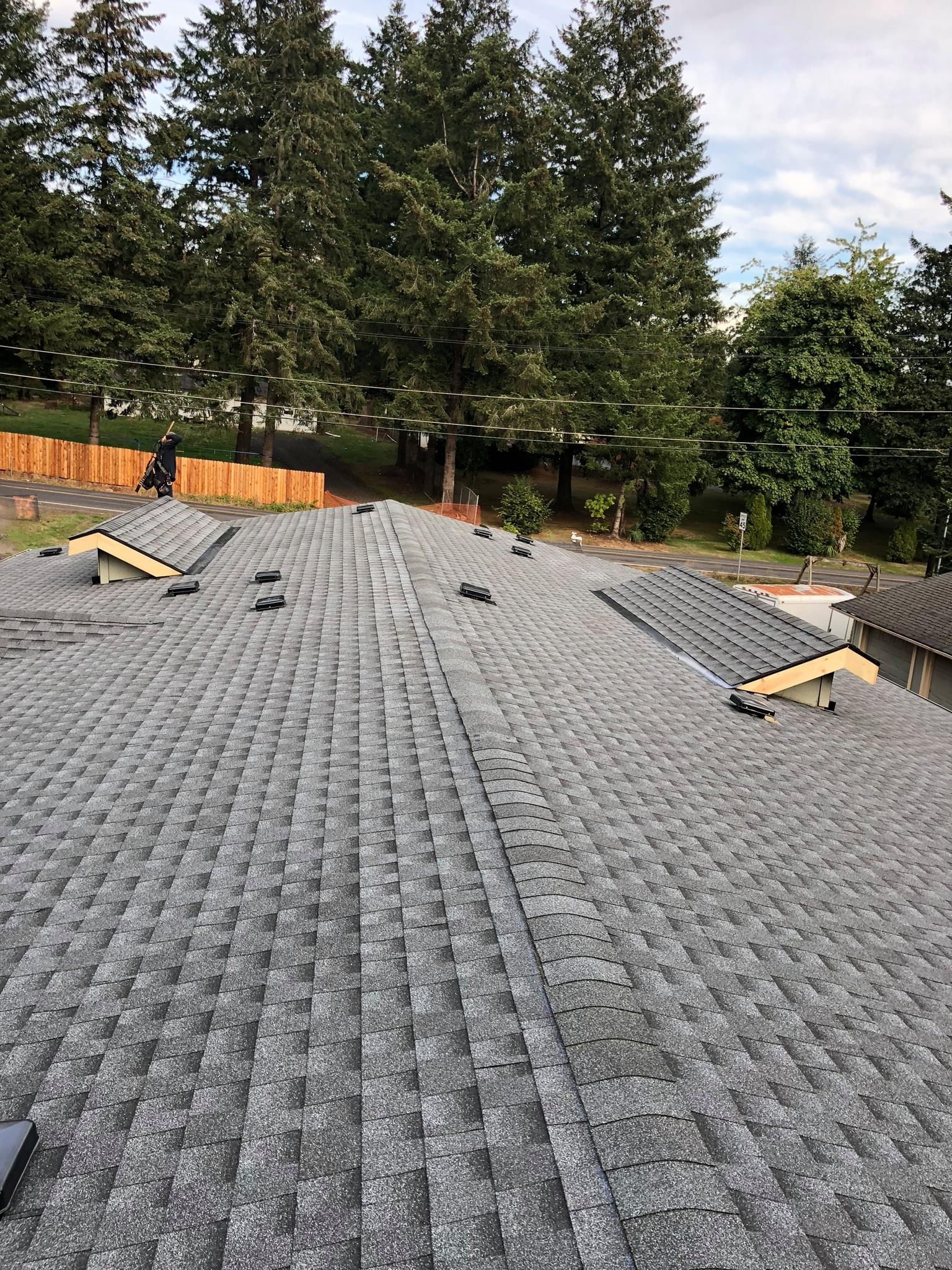 A roof with a lot of shingles on it and trees in the background.