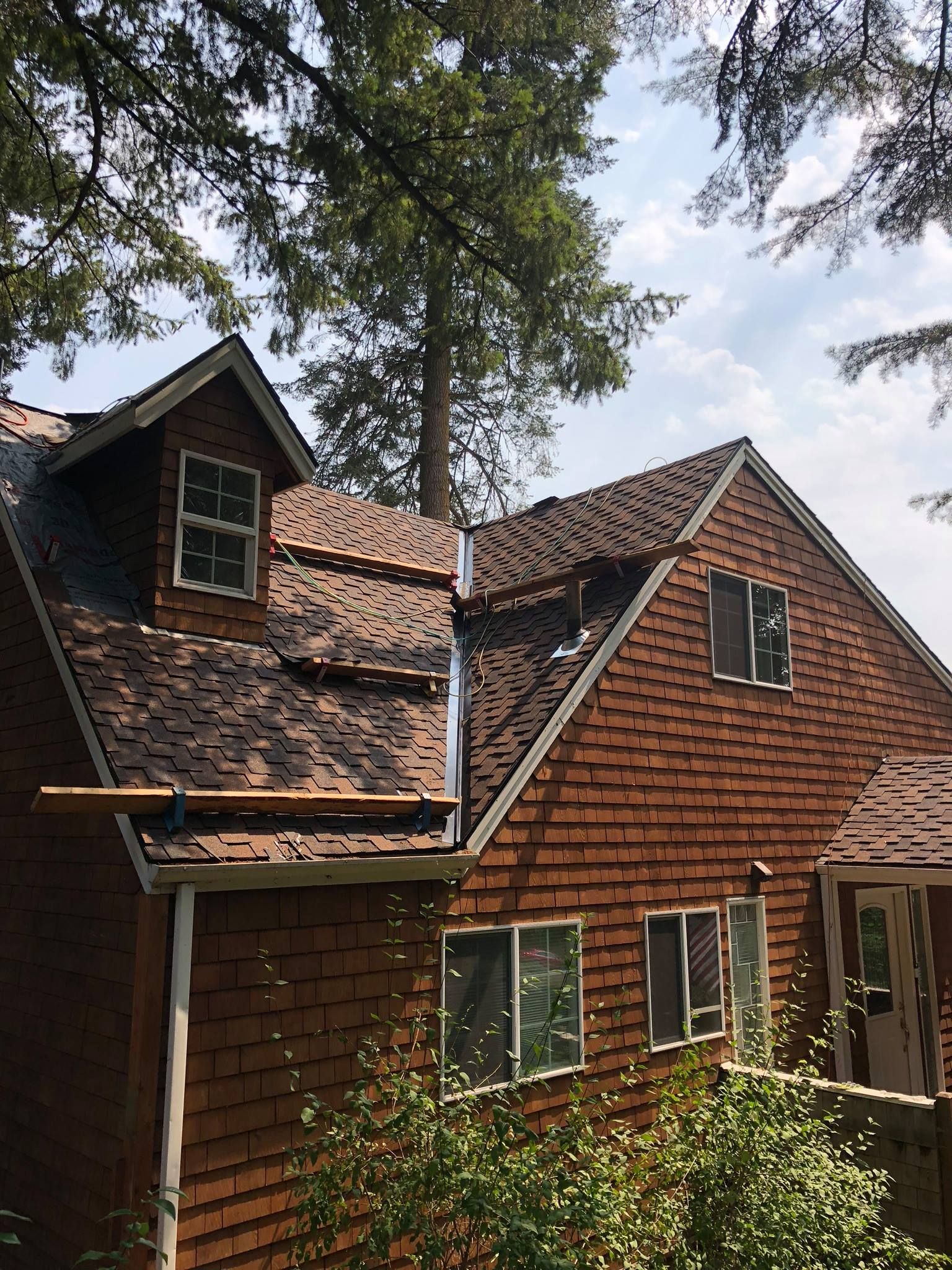 A house with a roof that has been damaged by a tree.