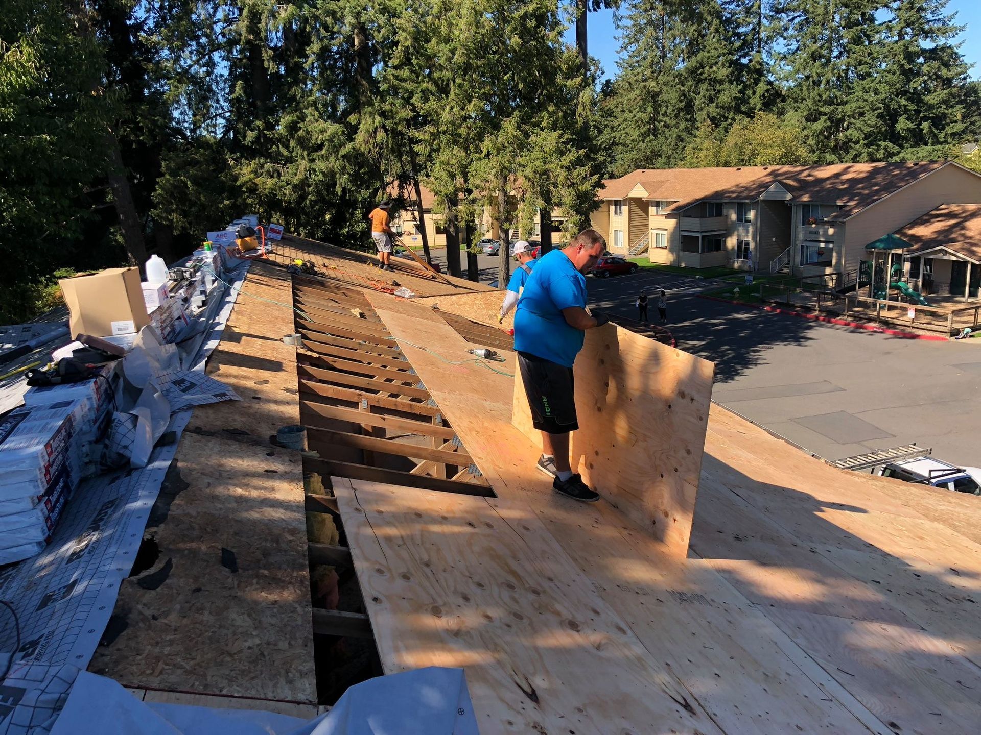 A man is standing on top of a wooden roof.