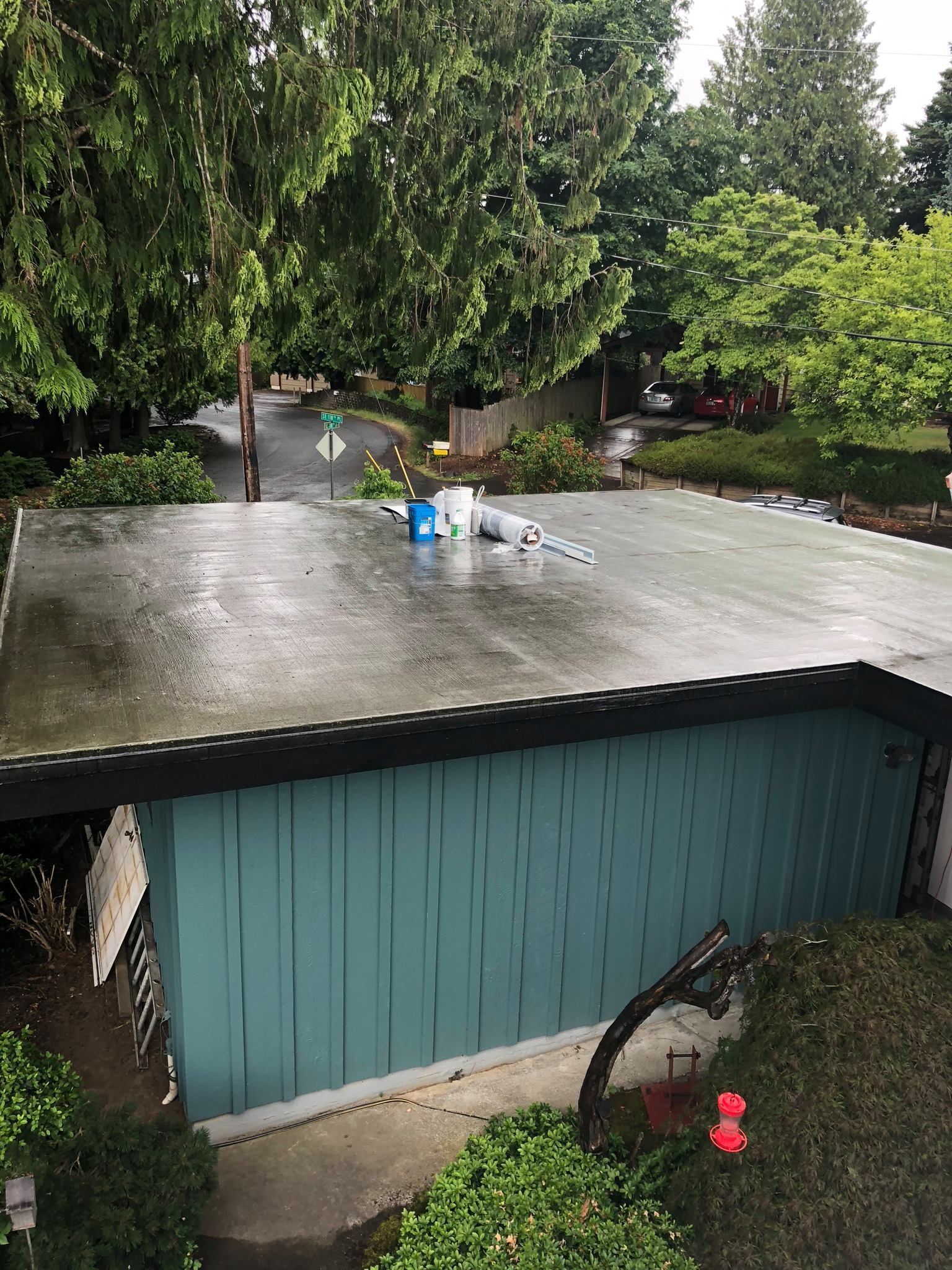 A blue garage with a roof that is covered in rain.