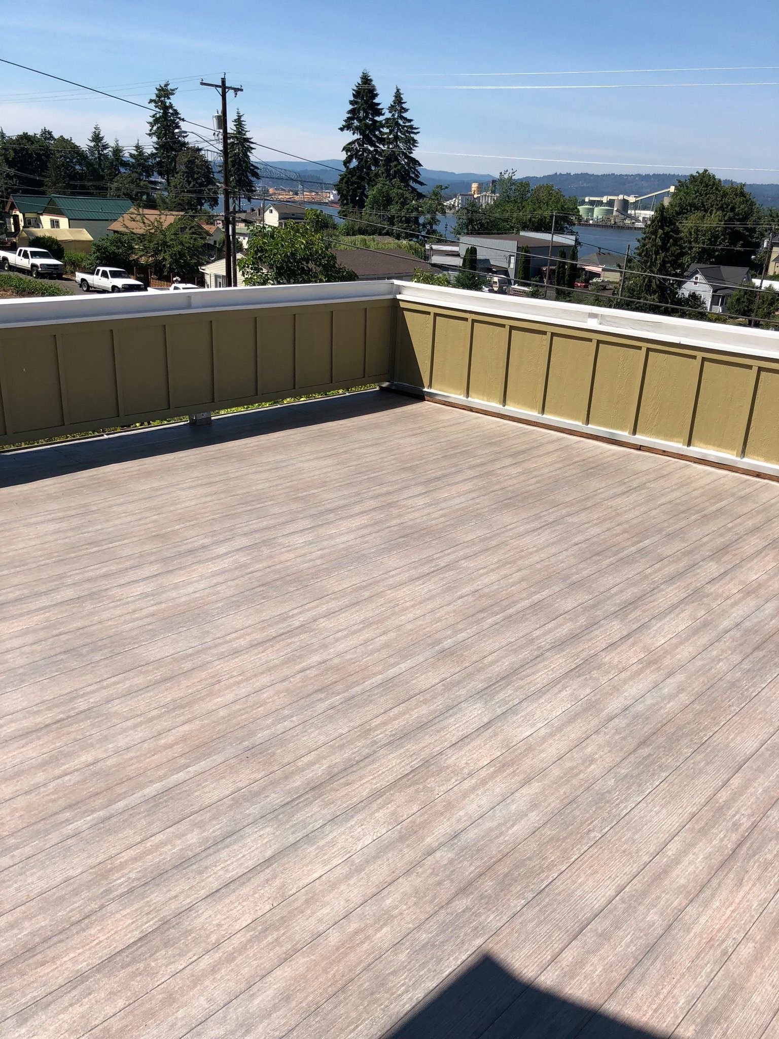 A rooftop deck with a view of a city and trees.