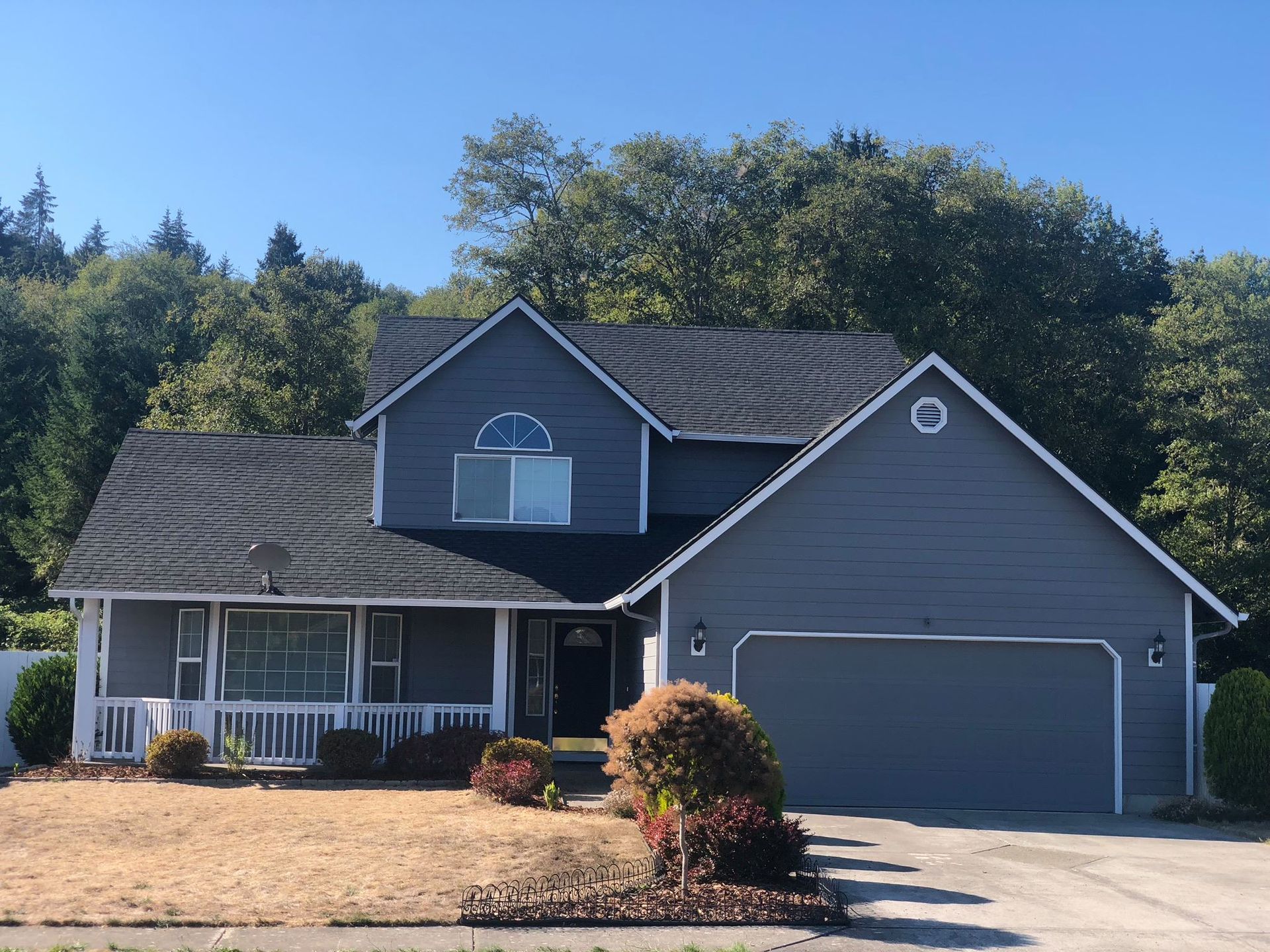 A gray house with a black roof and a white porch.