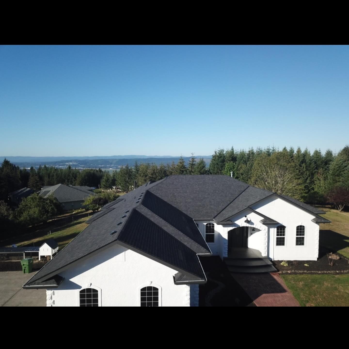 An aerial view of a large white house with a black roof.