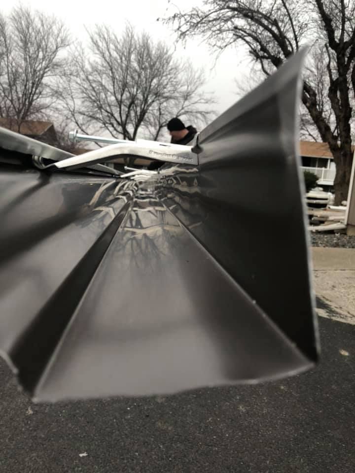 A man is working on a gutter on a roof.
