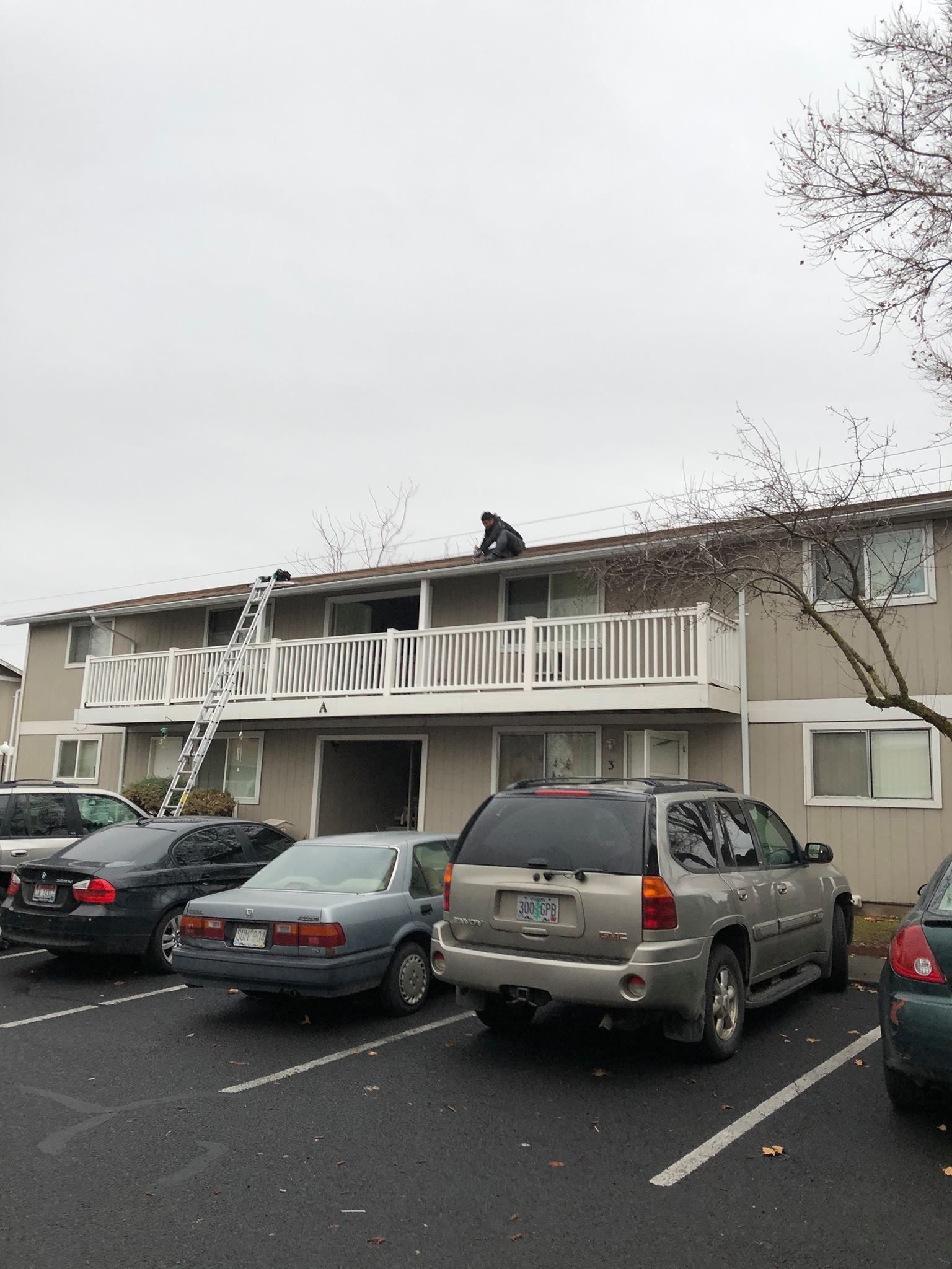 A building with cars parked in front of it and a man on the roof.