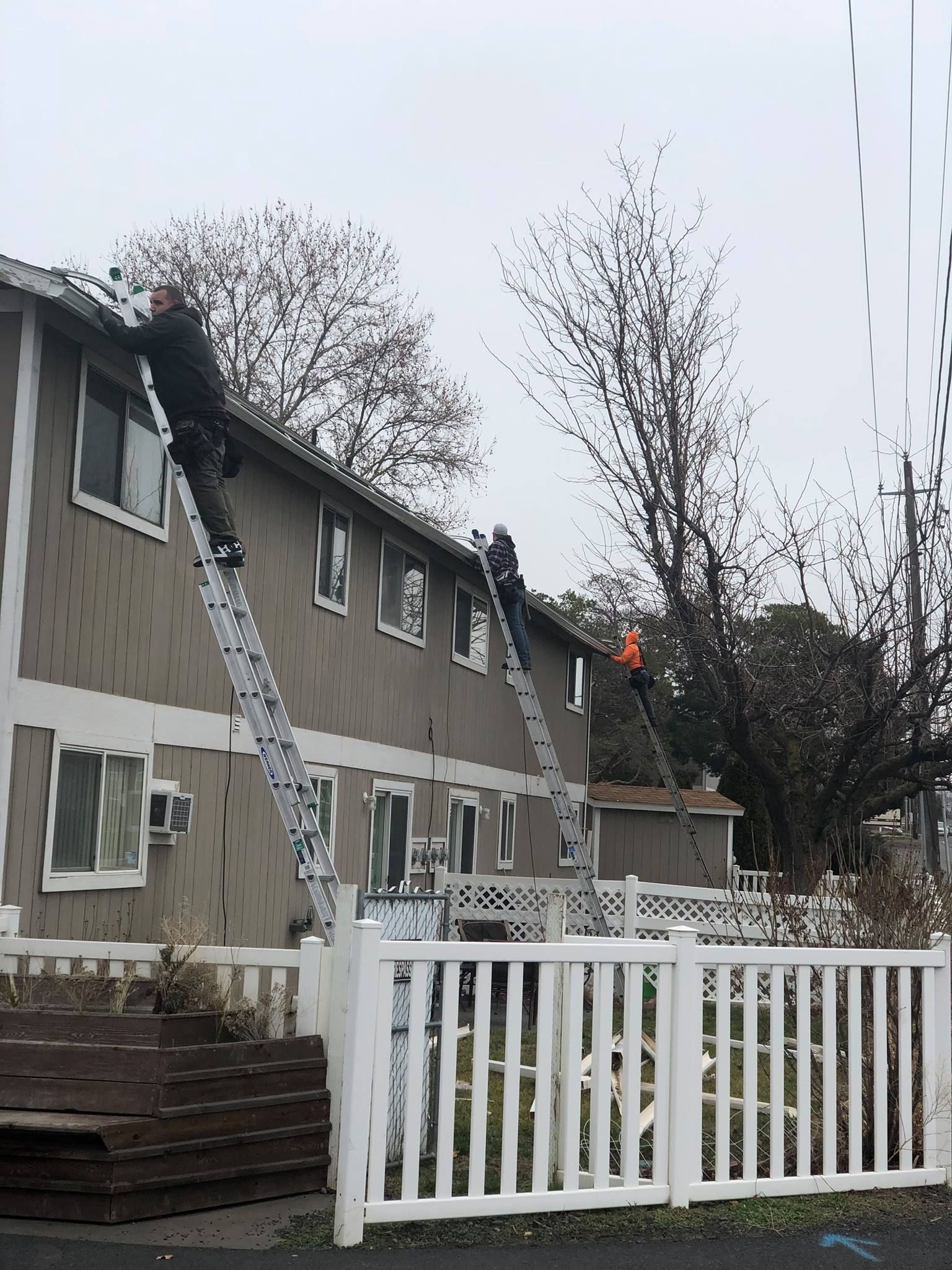 A man is standing on a ladder on the roof of a building.