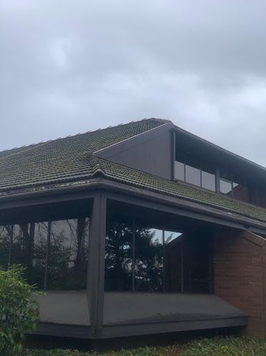 A large brick building with a green roof and lots of windows on a cloudy day.