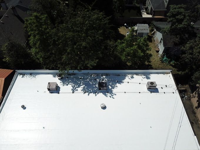 An aerial view of a white roof with trees in the background.