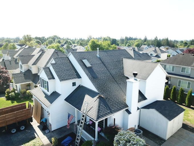 An aerial view of a white house with a black roof.