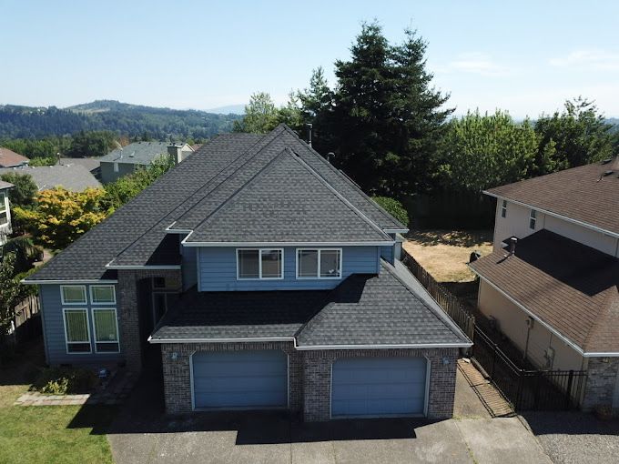 An aerial view of a blue house with a black roof.
