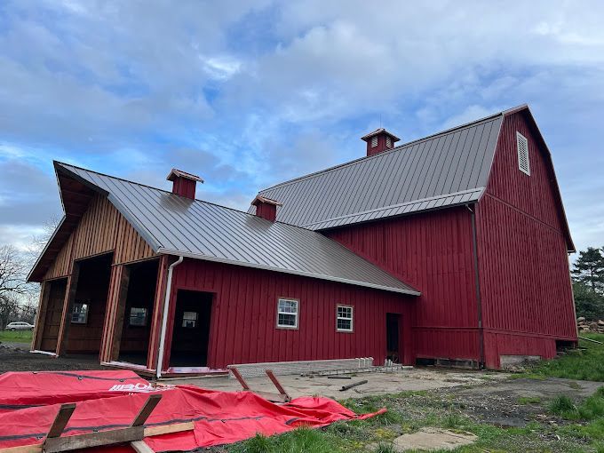 A large red barn with a metal roof is being built.