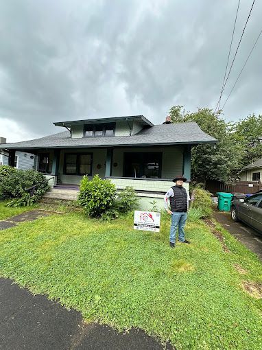 A man is standing in front of a house holding a sign.