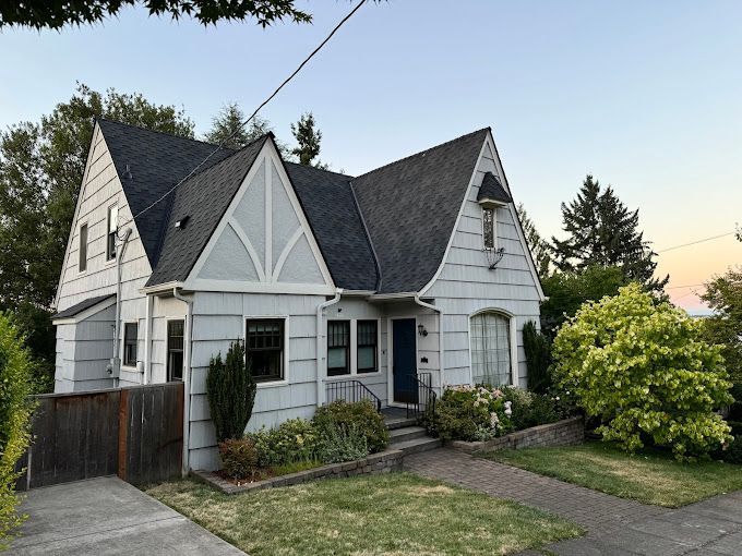 A white house with a black roof and a blue door.