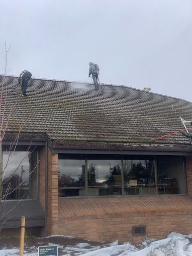 A couple of people are cleaning the roof of a house.