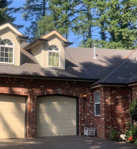 A brick house with two garage doors and a gray roof.