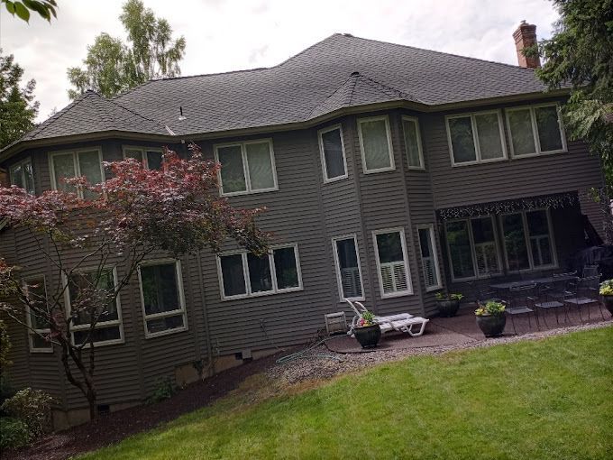 A large house with a lot of windows is sitting on top of a lush green hillside.