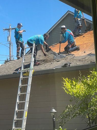 A group of men are working on the roof of a house.