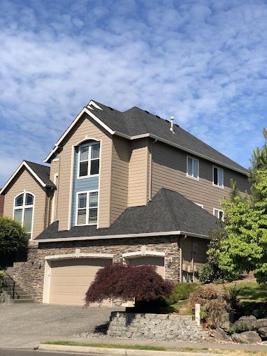 A large house with a black roof and a garage.