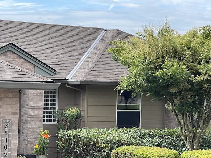 A house with a roof and a tree in front of it.