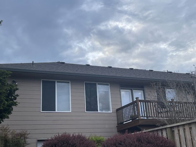 The back of a house with a balcony and a cloudy sky in the background.