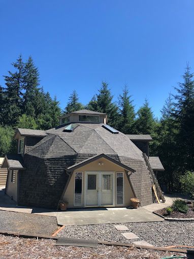 A dome shaped house is surrounded by trees on a sunny day.