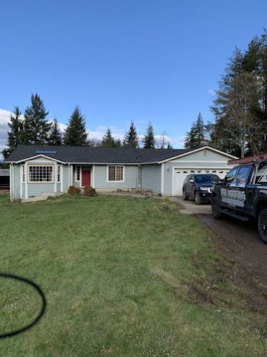 A blue house with a black truck parked in front of it.