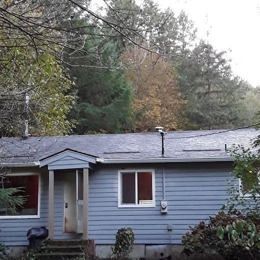 A blue house with a roof that is covered in shingles.