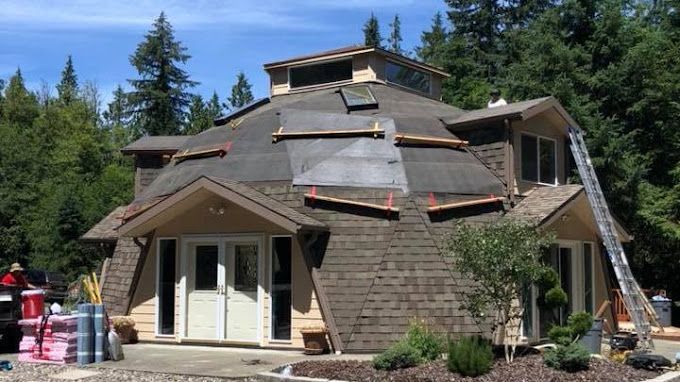 A dome shaped house is being built in the middle of a forest.