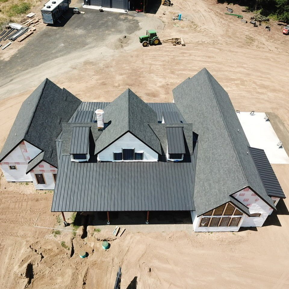 An aerial view of a large house with a black roof.