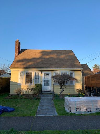 A yellow house with a brown roof is sitting on top of a lush green lawn.