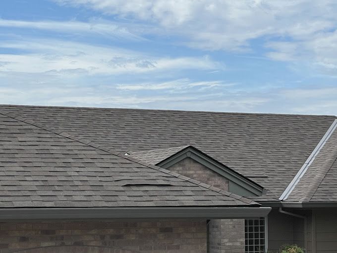 A house with a gray roof and a blue sky in the background.