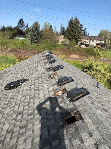 A roof with a lot of vents on it and a shadow of a person on it.