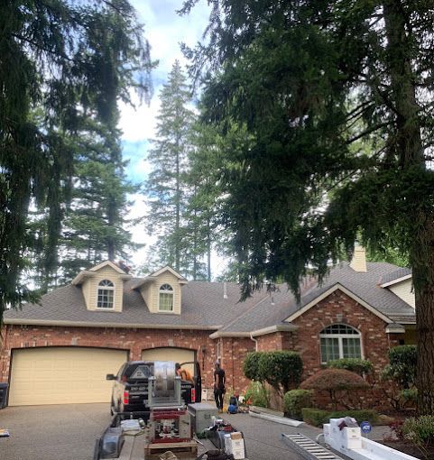 A truck is parked in front of a brick house surrounded by trees.