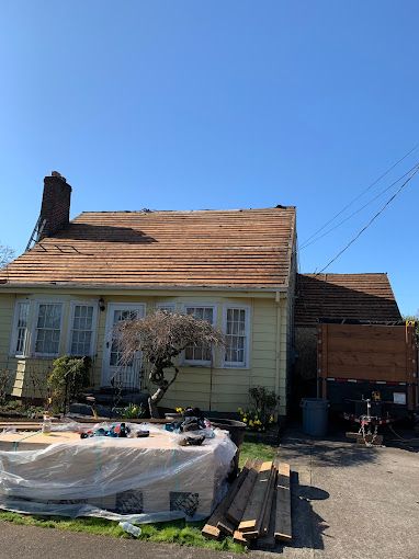 A yellow house with a wooden roof is being remodeled.