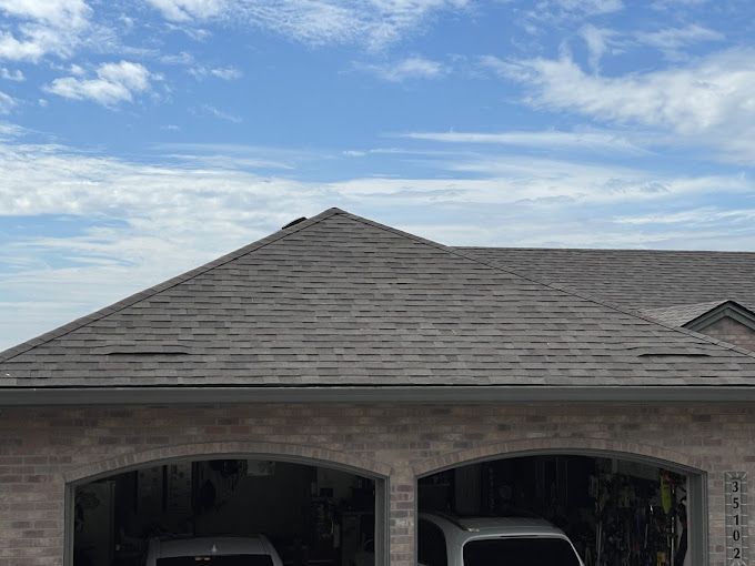 A car is parked in a garage next to a house with a roof.