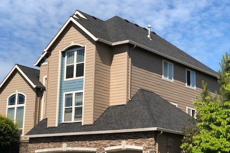 A large house with a black roof and a lot of windows.
