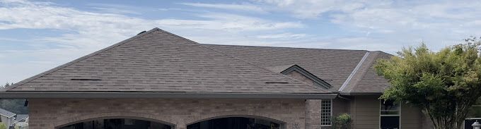 A large brick house with a gray roof and a garage.