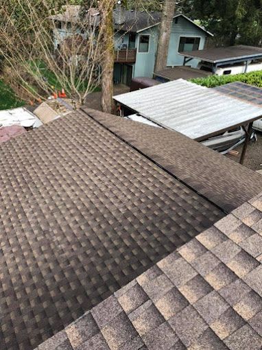 A roof with a lot of tiles on it and a house in the background.