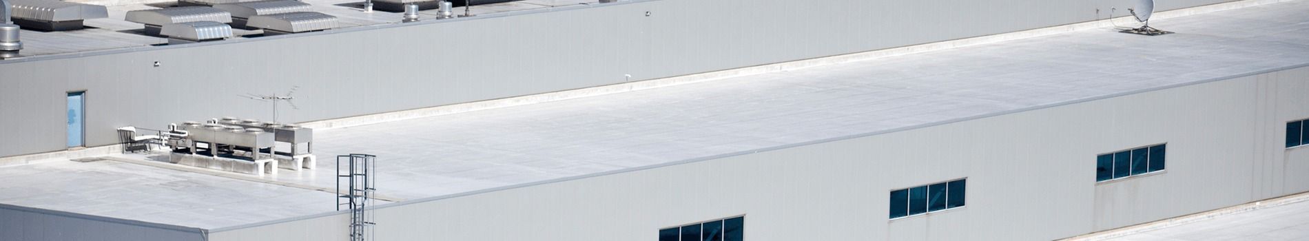 An aerial view of a large white building with snow on the roof.