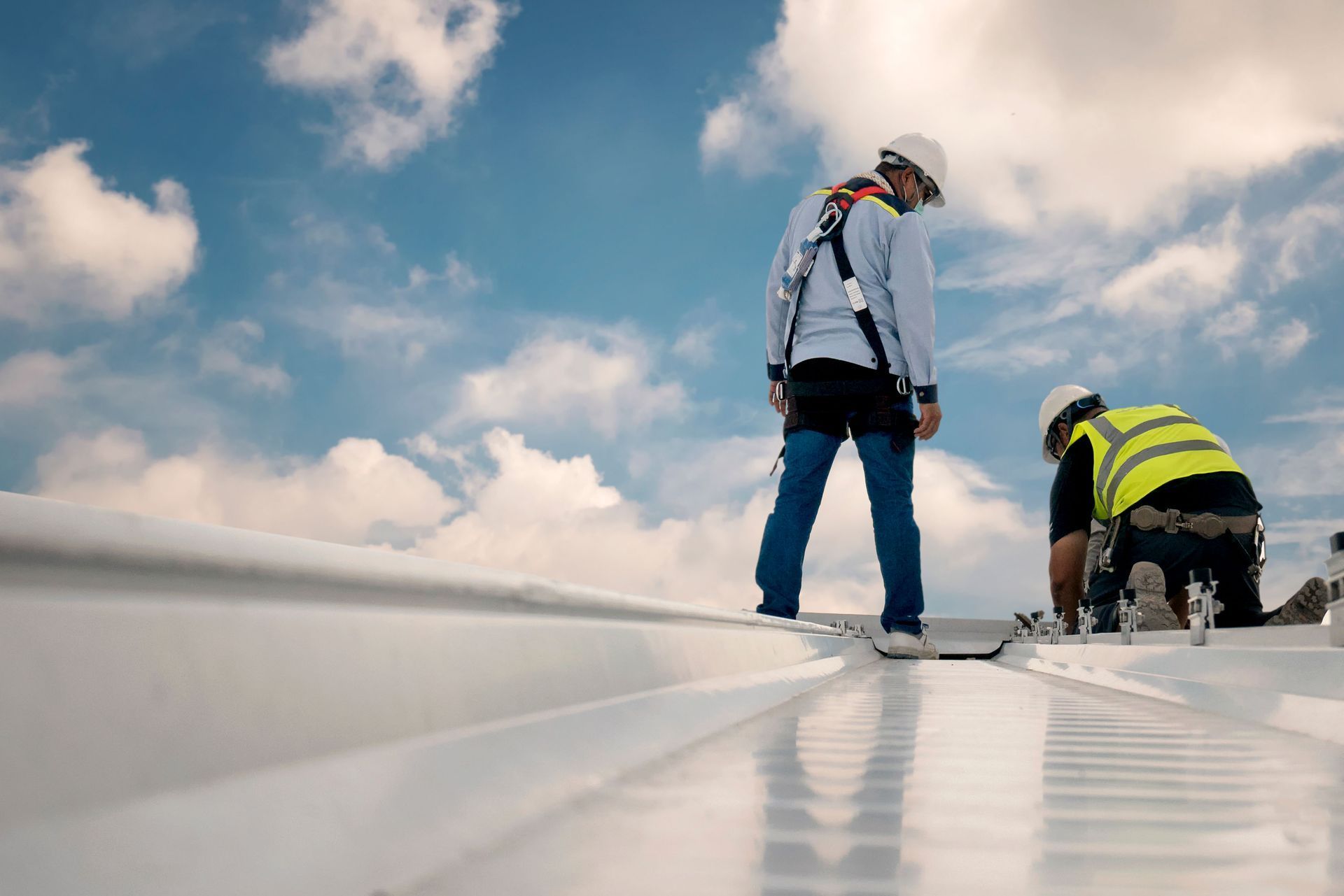Two construction workers are working on the roof of a building.