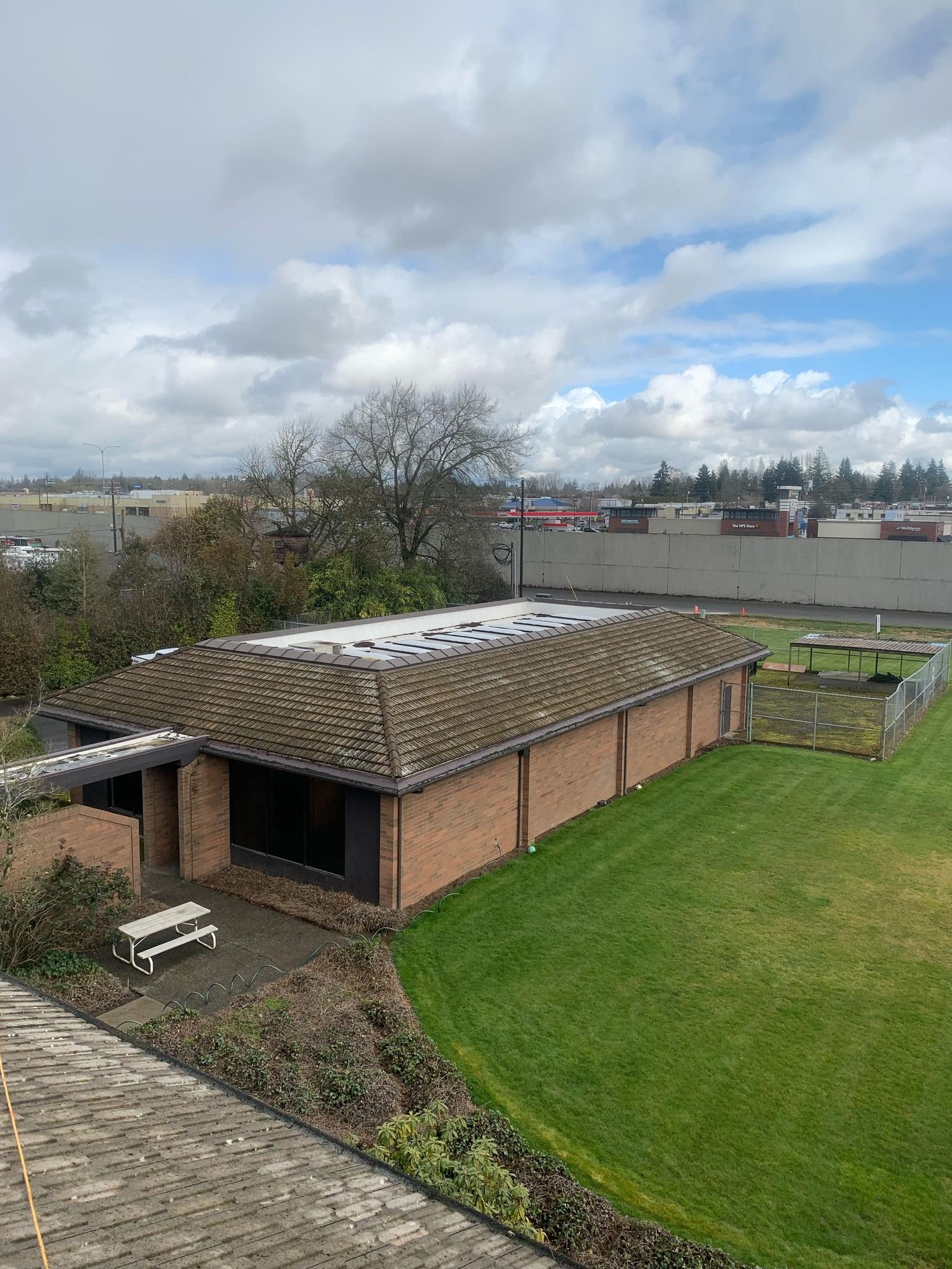 An aerial view of a brick building with a roof that is covered in moss.