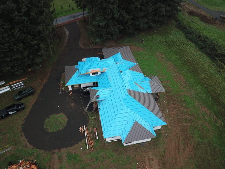 An aerial view of a house under construction with a blue roof.