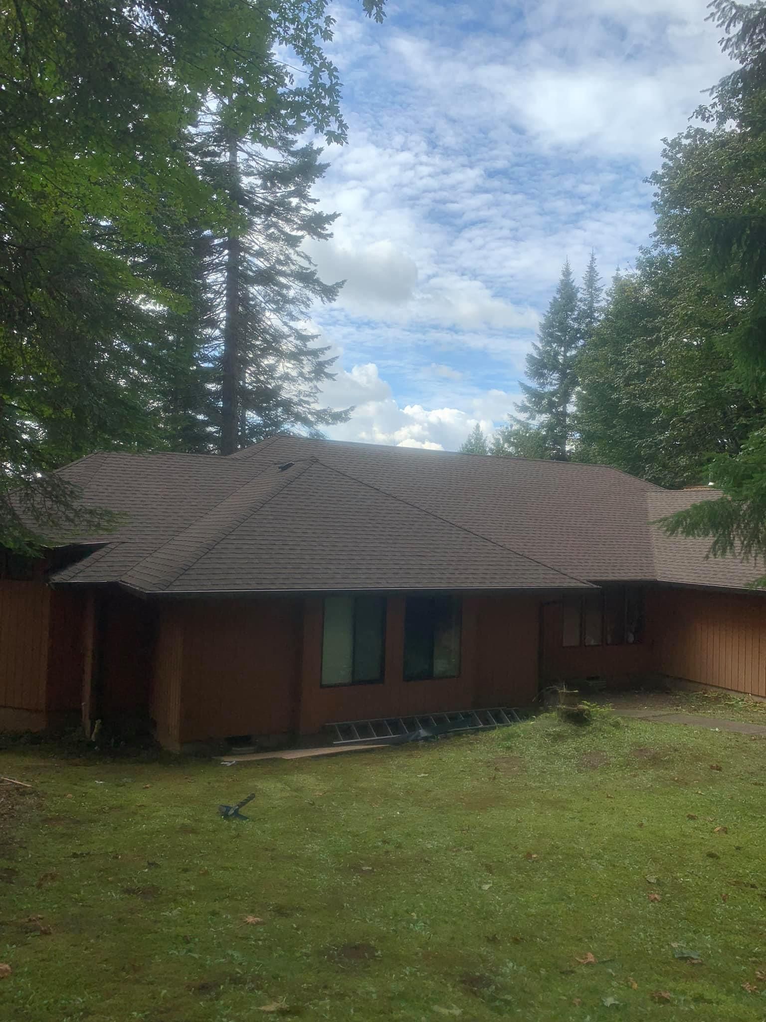 A house with a brown roof is surrounded by trees on a sunny day.