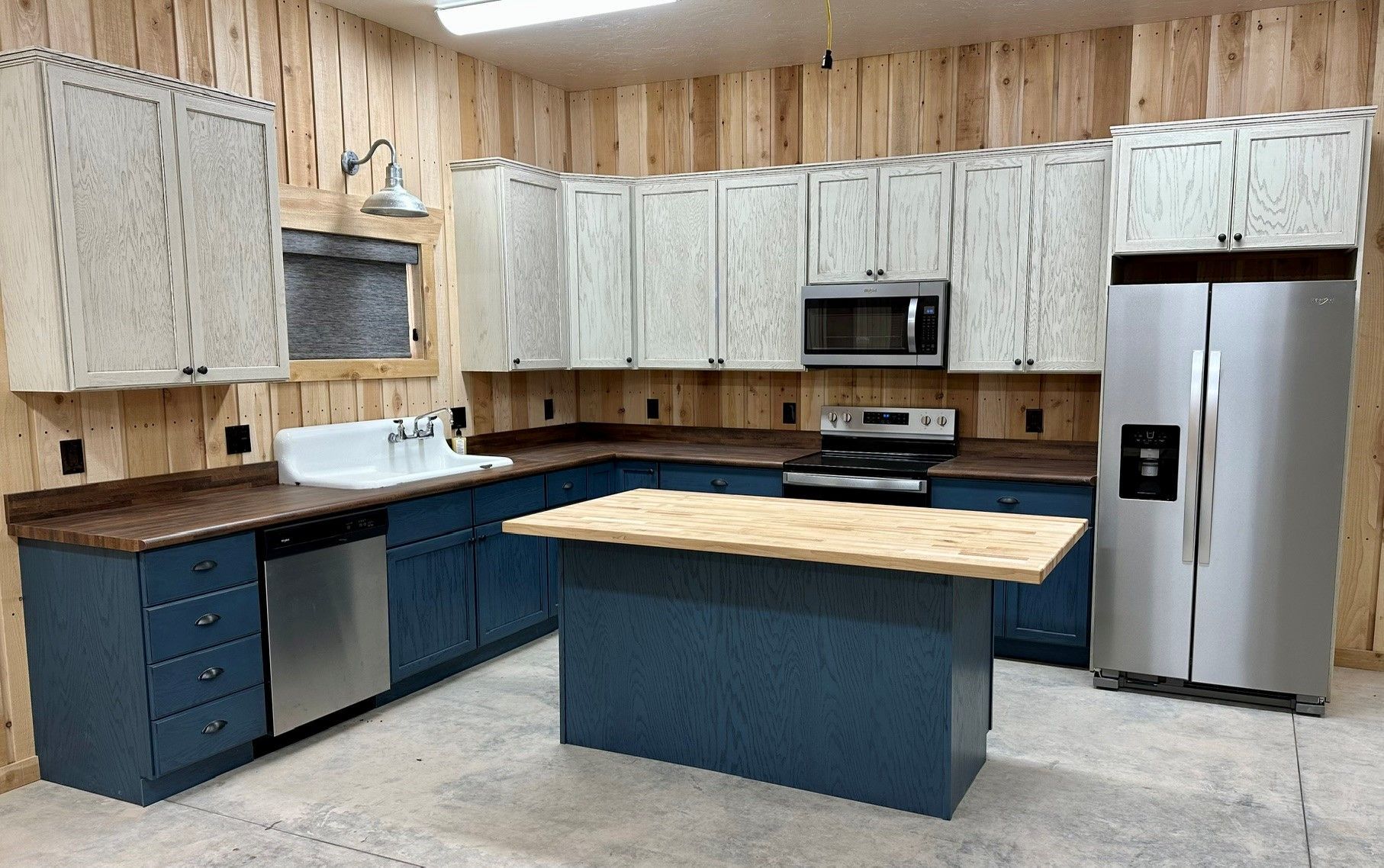 Modern kitchen with white cabinets, blue island, wood countertops, and stainless steel appliances