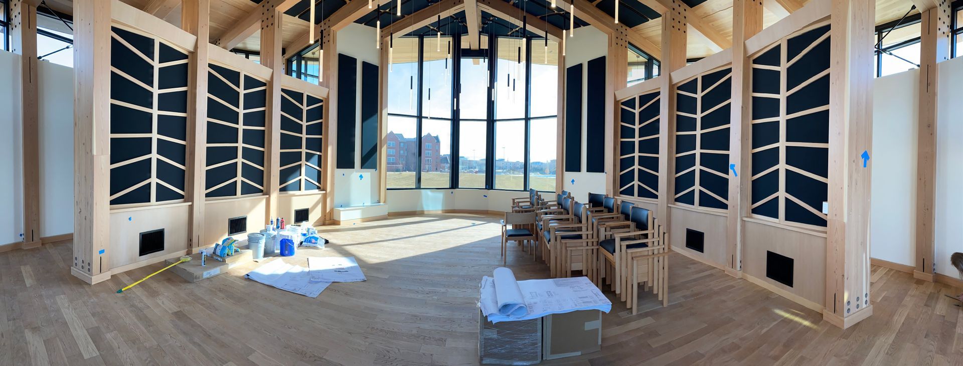 Interior of a house under construction with exposed framing, windows, and building materials on the floor.