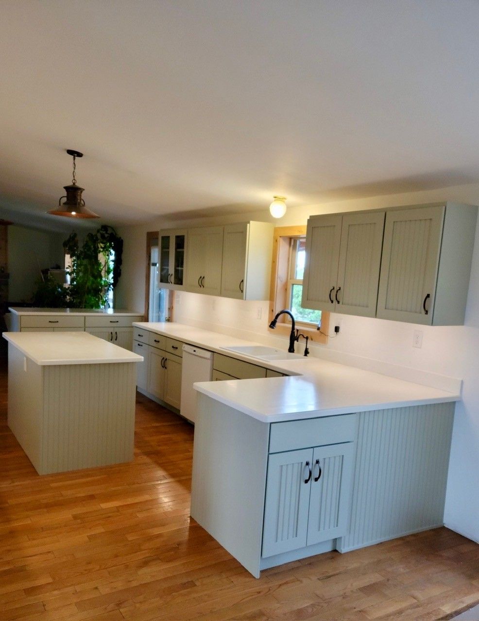 Bright kitchen with white cabinets, island, and hardwood floors, viewed from an open dining area