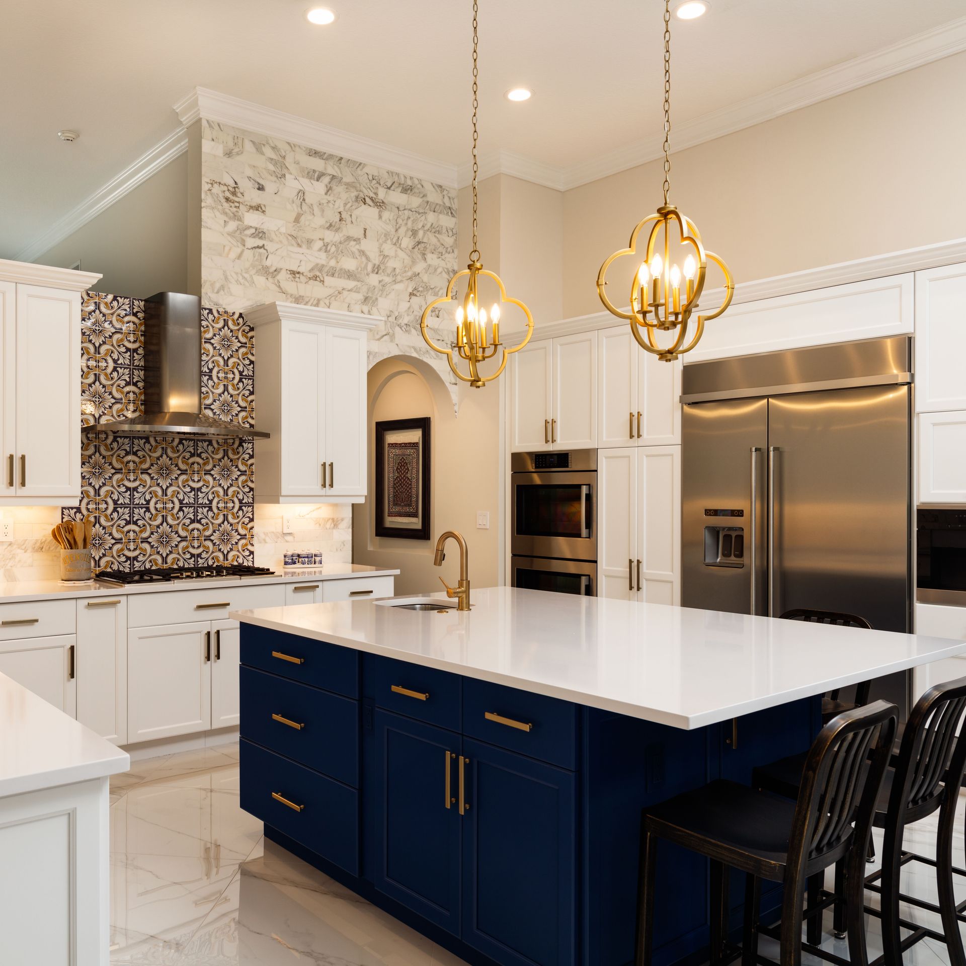 Bright modern kitchen with navy island, white cabinets, stainless steel appliances, and gold pendant lights