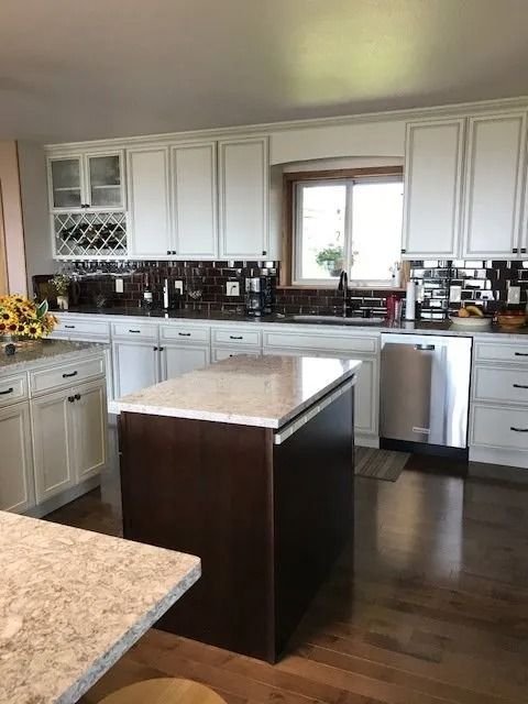 Bright kitchen with white cabinets, dark wood island, and stainless steel appliances