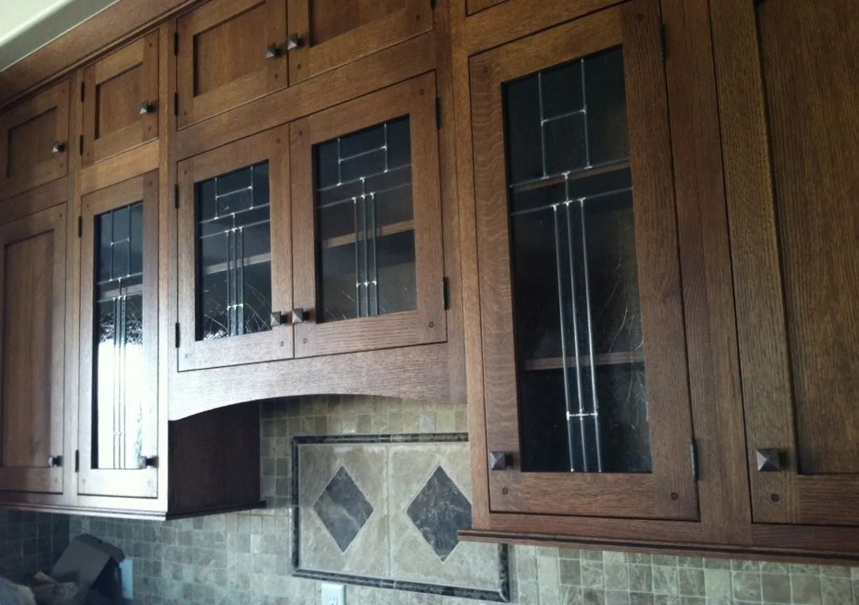 Wooden kitchen cabinets with glass-paneled doors above a tiled backsplash.