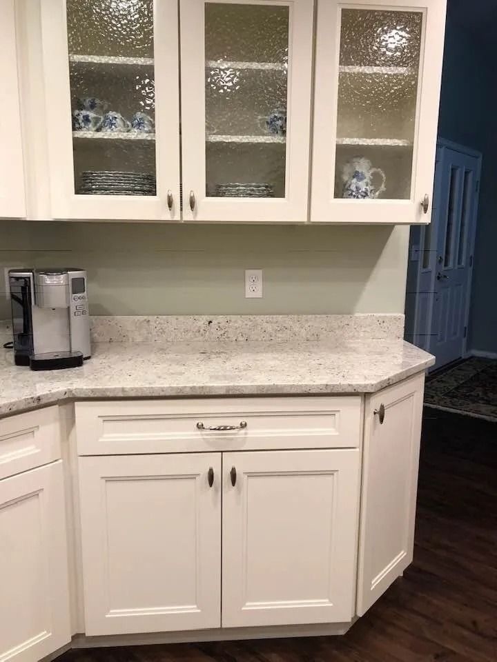 Kitchen with white cabinets, speckled granite countertop, coffee maker, and dark wood floor
